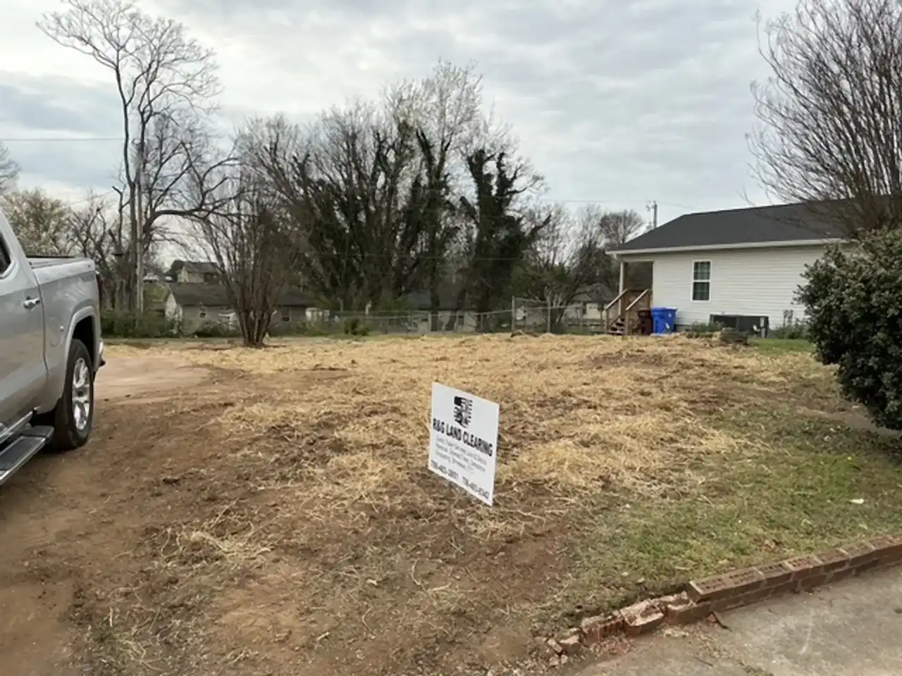 Cleared and graded lot after a house demolition, with the company yard sign out front, R&G Land Clearing