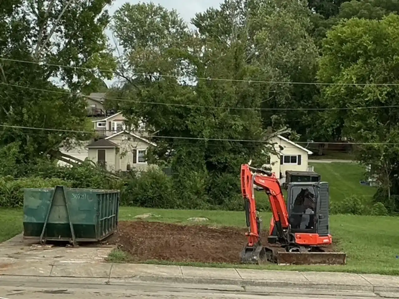 Kubota excavator and roll-off dumpster on a cleared lot after a home teardown, R&G Land Clearing