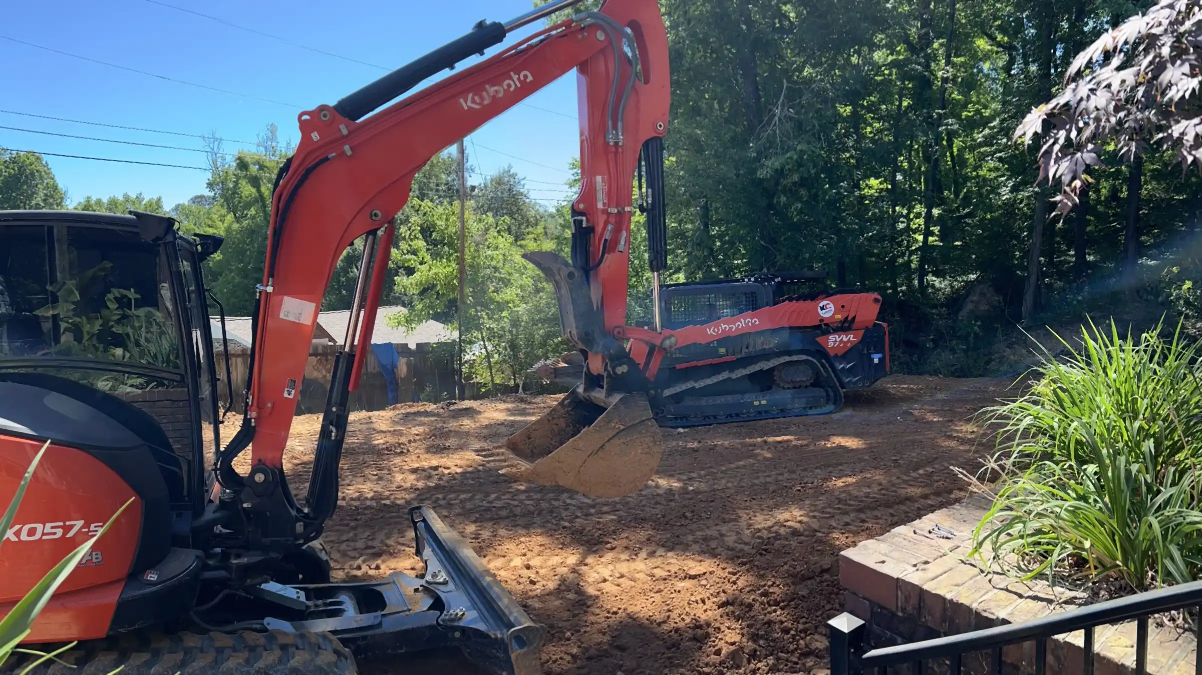 R&G Land Clearing's Kubota excavator clearing and grading a lot beside a home