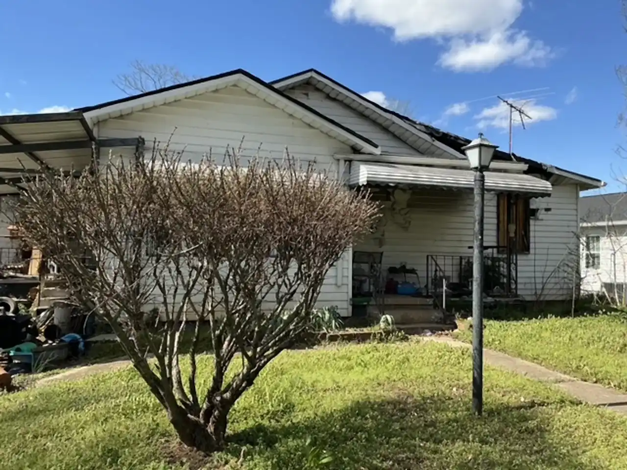 Single-story house with metal awnings before demolition, R&G Land Clearing
