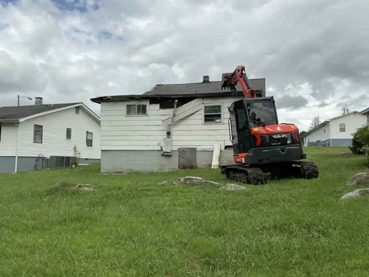 Kubota excavator starting a teardown at the rear wall of a house, R&G Land Clearing