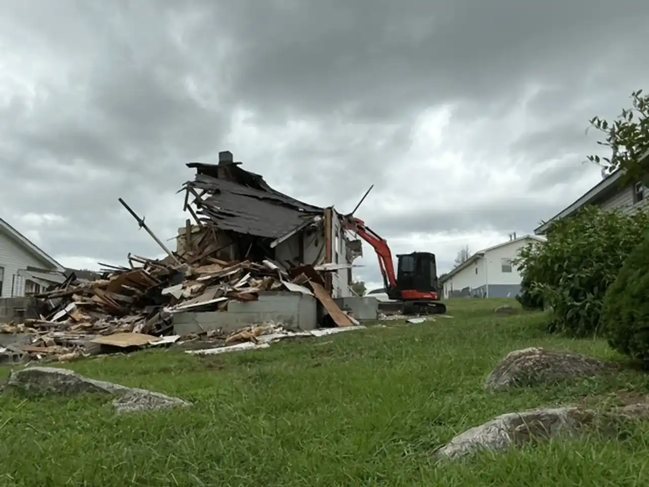 Excavator tearing down a single-story house, roof and walls collapsing into the debris pile, R&G Land Clearing