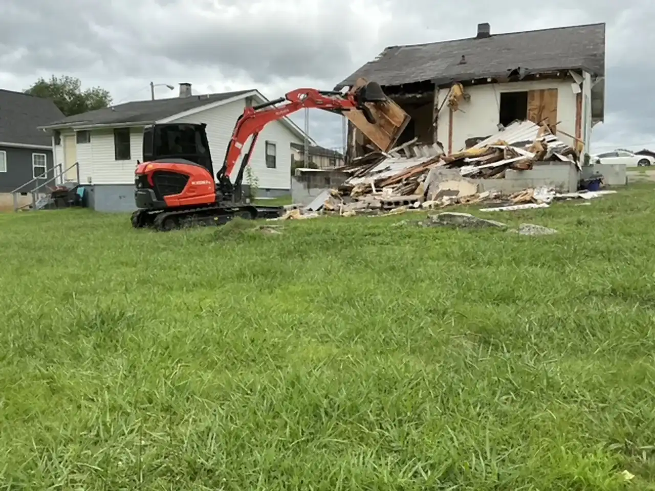Kubota excavator opening up the side wall of a house during demolition, R&G Land Clearing