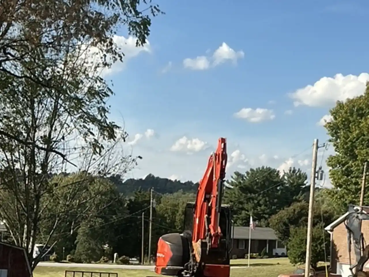 Kubota excavator spreading and grading fill dirt over a pool fill-in, R&G Land Clearing