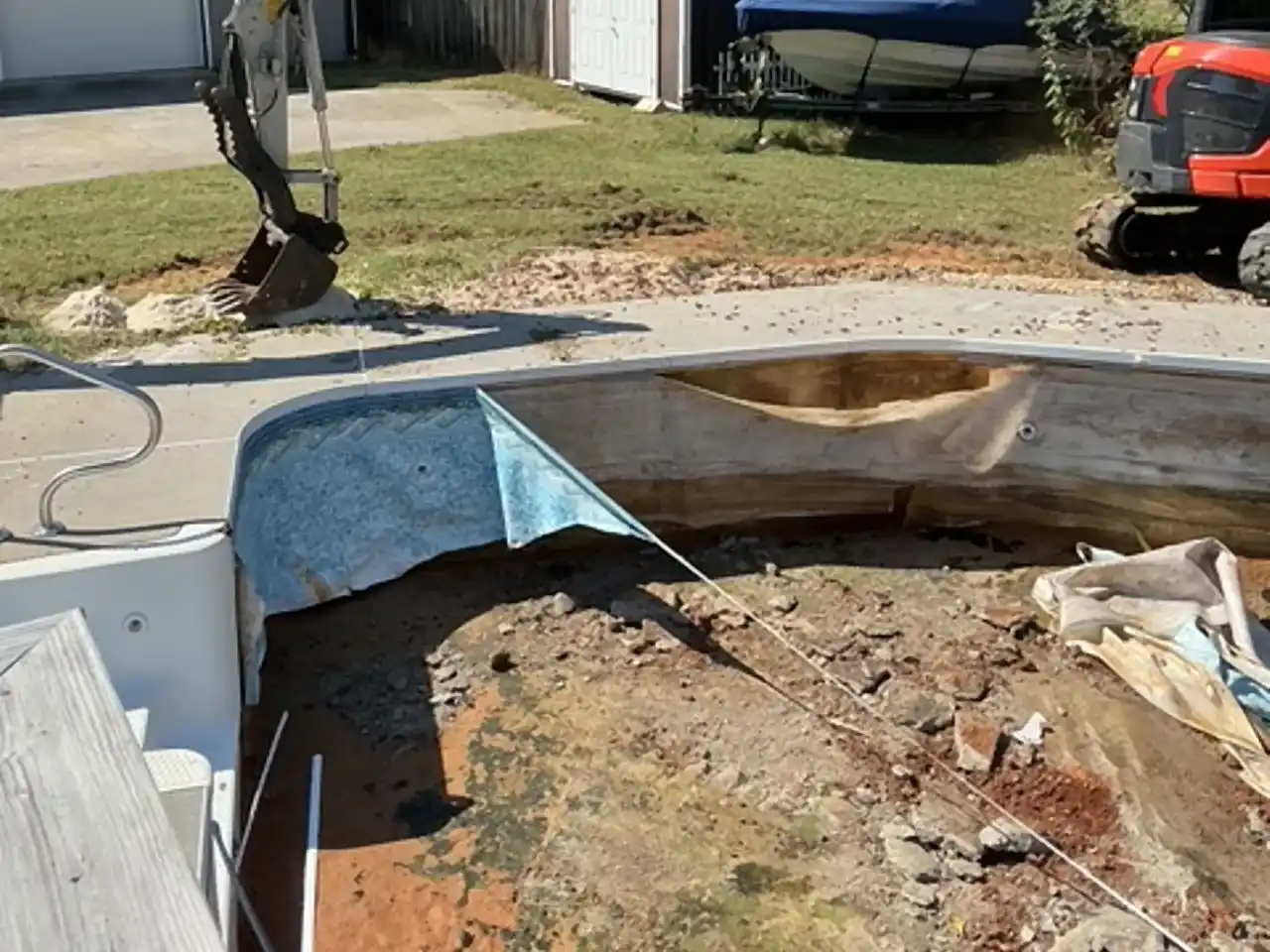 Excavator bucket breaking up the shell of an emptied in-ground pool, R&G Land Clearing