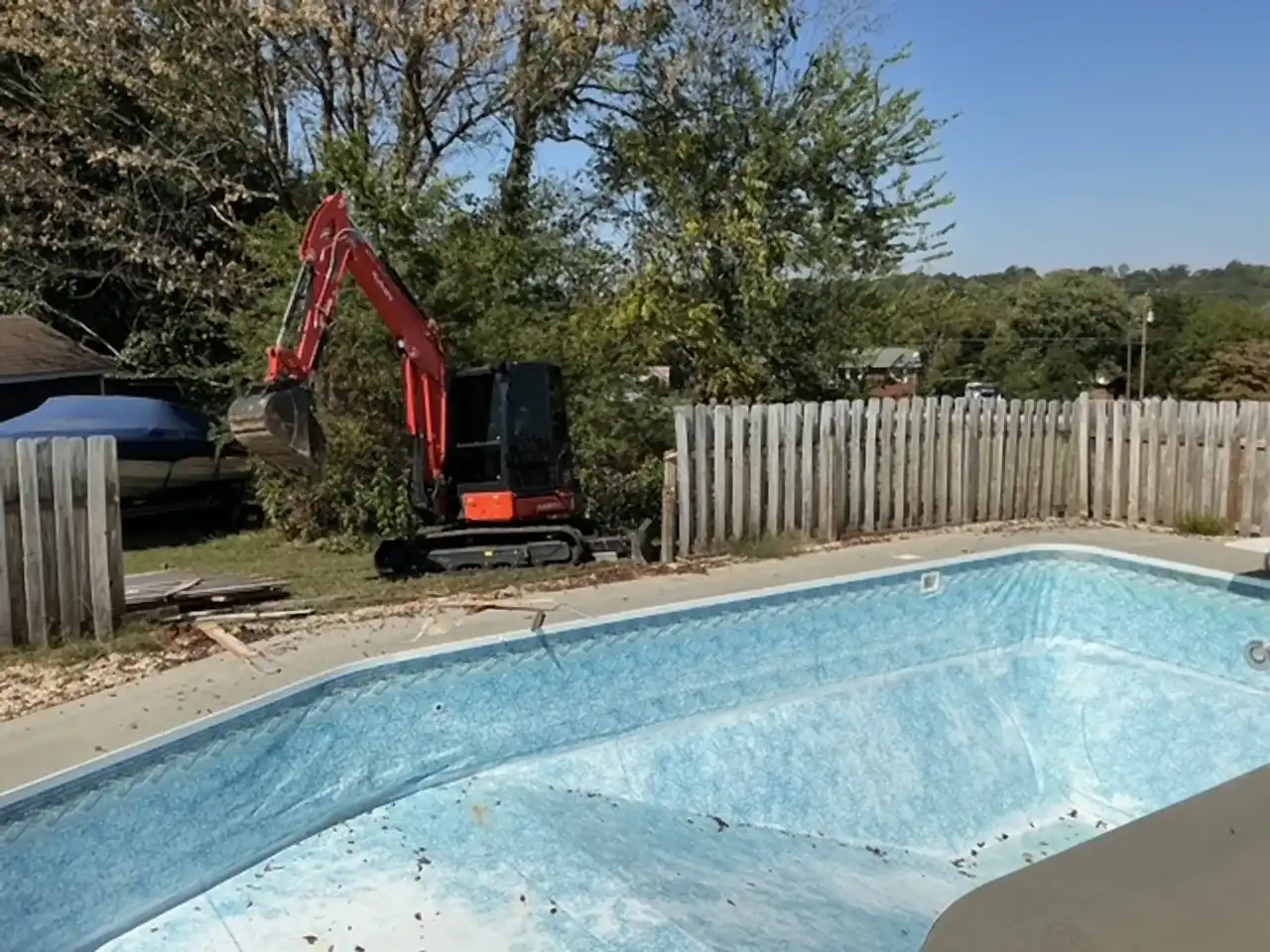 Kubota excavator beside a drained in-ground pool, ready to break out the shell, R&G Land Clearing